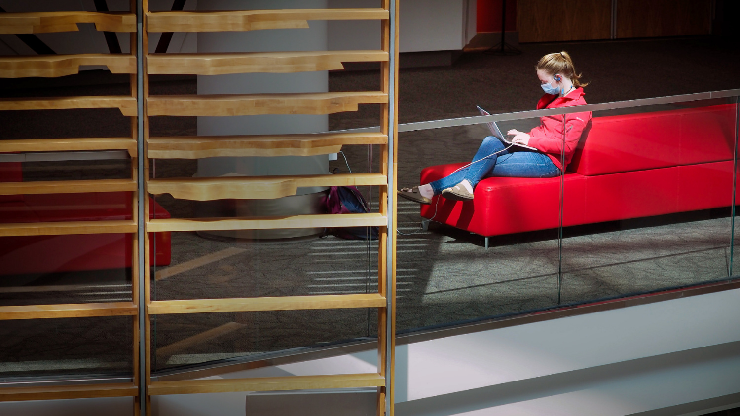 Student sits on a red couch in Talley Student Center working on her laptop.